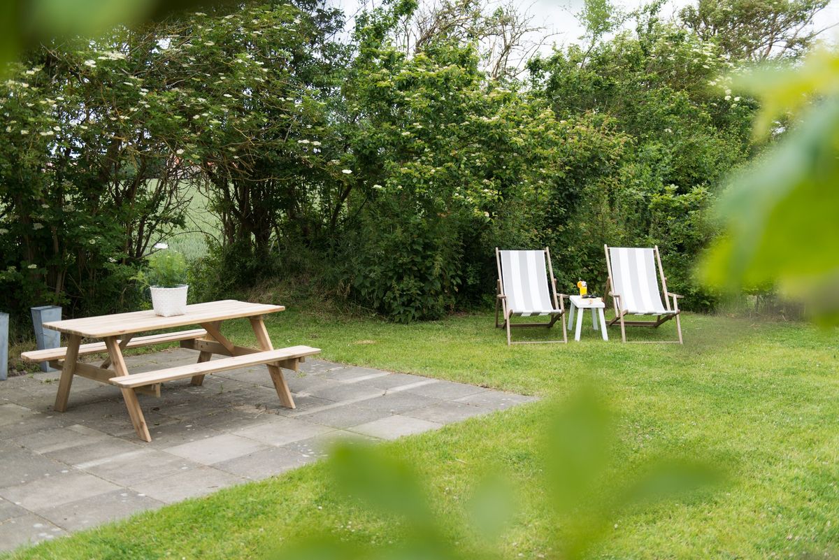 Tuin met picknicktafel en ligstoelen – Zeeuwshuisje vakantiewoning, Koudekerke