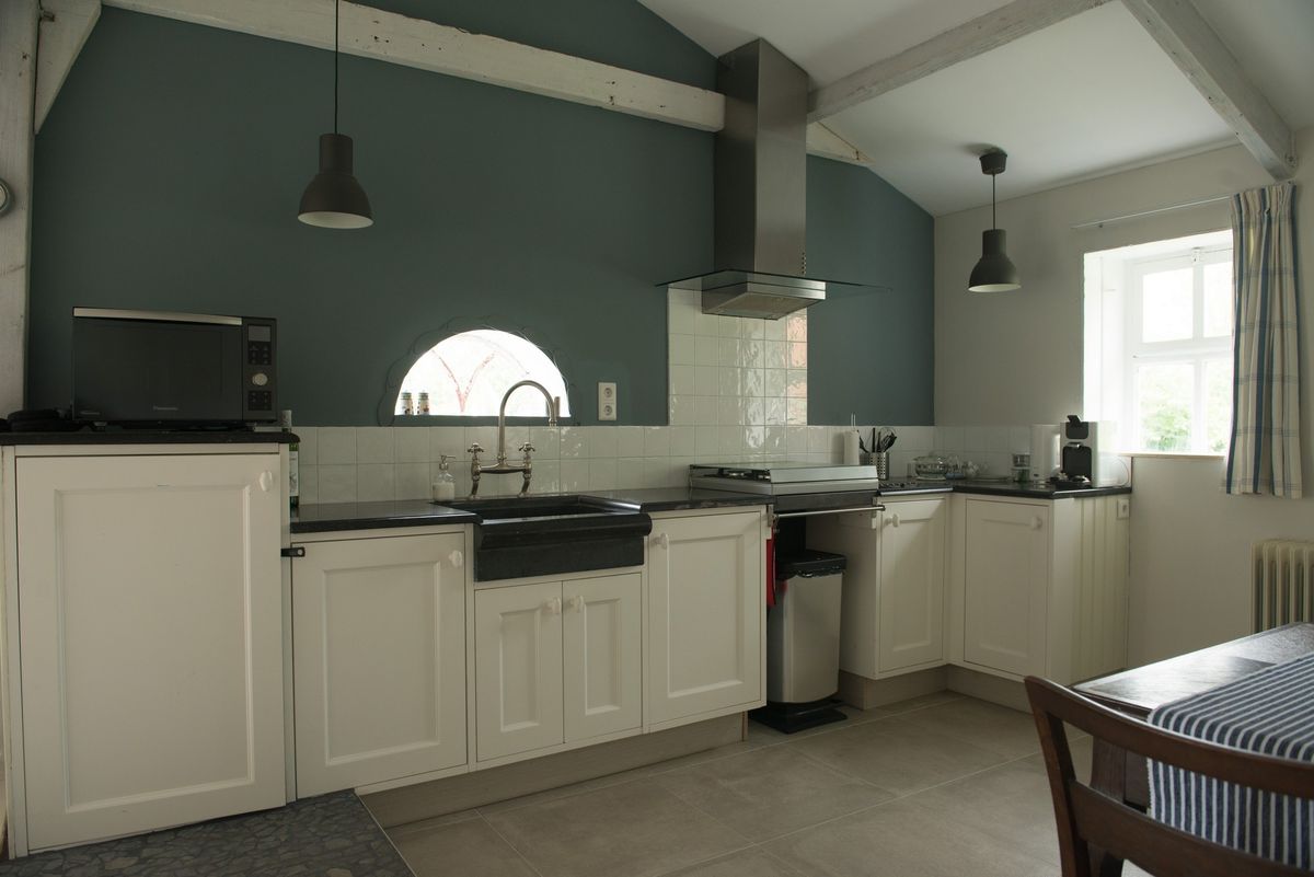 Volledige keuken met witte kasten, roestvrijstalen afzuigkap en donkergroene muren – Zeeuwshuisje vakantiewoning, Koudekerke