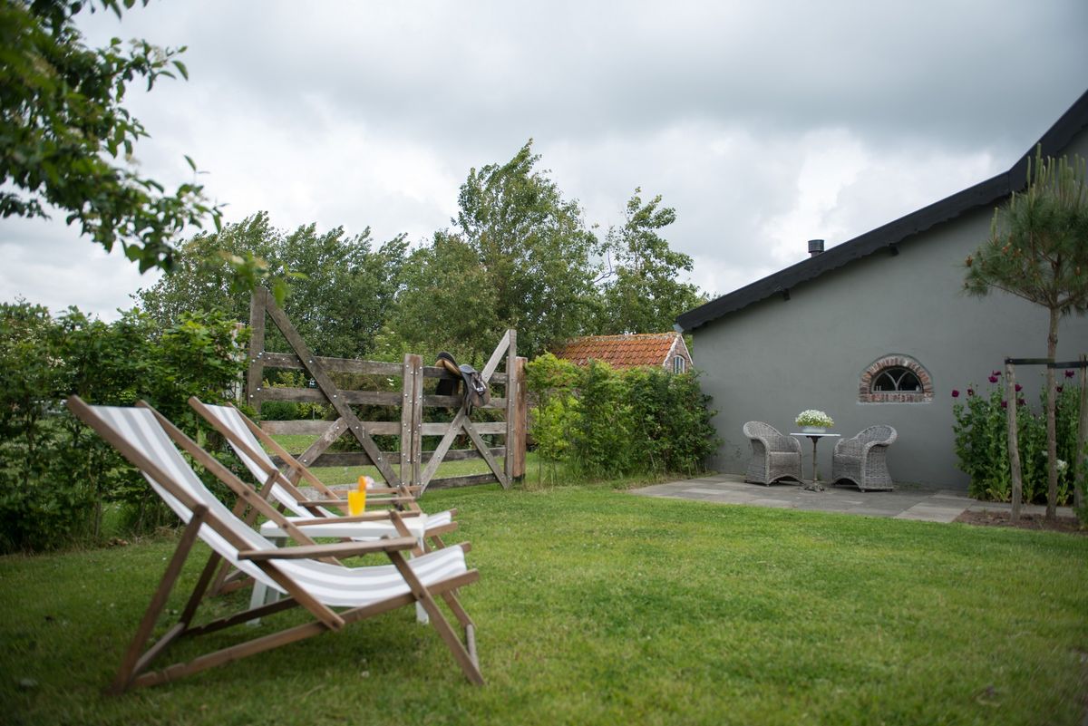 Zonnige tuin met ligstoelen en gazon – Zeeuwshuisje vakantiewoning, Koudekerke